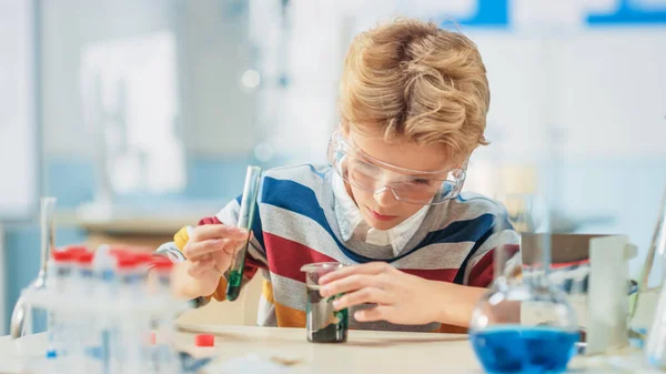 Basisschool Wetenschap of Scheikunde Klaslokaal: Smart Little Boy draagt veiligheidsbril Mixes Chemicals in Beakers — Stockfoto