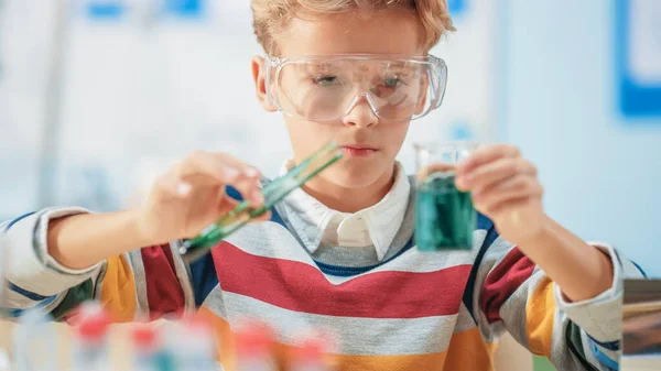 Aula de Ciencia o Química de la Escuela Primaria: Niño inteligente con gafas de seguridad mezcla productos químicos en vasos de precipitados — Foto de Stock