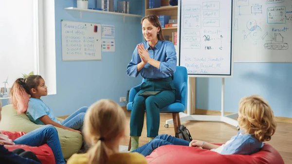 Elementary School Creativity Class: Kinderen zitten op de Bonentassen terwijl de Leraar Lessen en Vragen uitlegt. Leren in een moderne omgeving. — Stockfoto