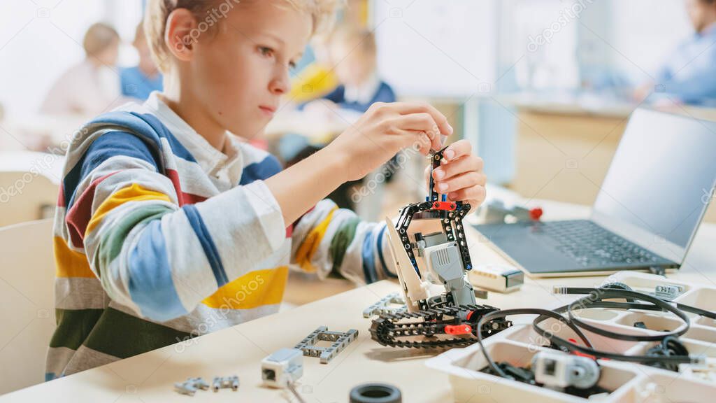 Schoolboy Builds Constructs Small Robot and Uses Laptop to Program Software for Robotics Engineering Class. Elementary School Science Classroom with Gifted Brilliant Children Working with Technology