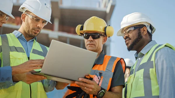 Diversi team di specialisti utilizzano il computer portatile sul cantiere. Progetto di Costruzione Immobiliare con Ingegnere Civile, Investitore Architettonico, Imprenditrice e Lavoratrice Piano di Discussione — Foto Stock