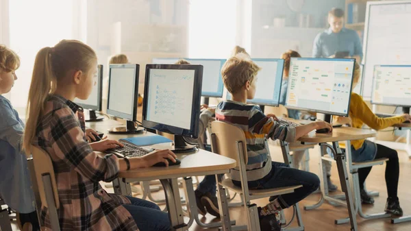 Elementary School Computer Science Classroom: Piccoli studenti intelligenti lavorano sui personal computer, imparano il linguaggio di programmazione per la codifica del software. Studenti ottenere l'educazione moderna — Foto Stock