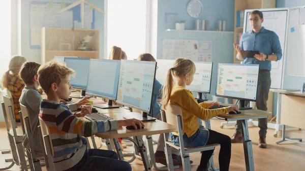 Sala de aula de ciências da escola primária: professor educa crianças pequenas inteligentes que trabalham em computadores pessoais, aprendem a linguagem de programação para escolas de codificação de software Obtendo educação moderna — Fotografia de Stock