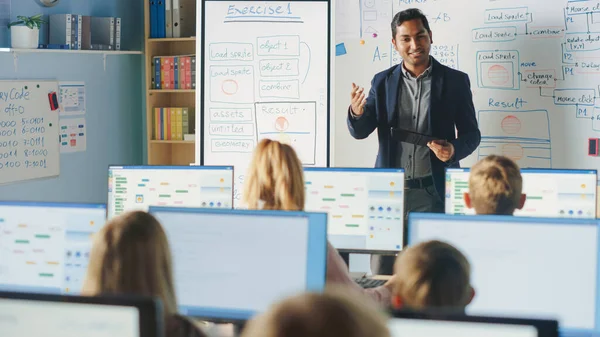 Informatikunterricht in der Grundschule: Lehrer benutzt digitales Tablet und erklärt verschiedenen Gruppen intelligenter Kinder den Unterricht. Kinder erhalten moderne Bildung, lernen Internetsicherheit, Softwareprogrammierung — Stockfoto