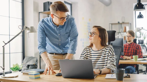 Les jeunes couples d'affaires occasionnels utilisent un ordinateur portable dans Creative Agency Loft. Amicale Easygoing Coworking Atmosphère. Ils discutent et réfléchissent à des idées. Gestionnaire expliquant une nouvelle stratégie de travail. — Photo