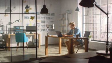 Profesyonel Yaratıcı Tasarımcı Çatı katında bir dizüstü bilgisayarda çalışıyor. Şık Tasarım veya Oyun İçeriği Geliştirme Stüdyosu. Güneş ışığı parlamasıyla çekilen.