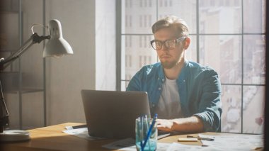 Yaratıcı Geliştirici Stüdyosunda Dizüstü bilgisayarda çalışıyor. Uygulamalar, Oyunlar ve Video Düzenleme Tasarımı. Arka plan Modern Sunny Çatı Ofisi 'nde Storyboard Projesi ve Duvarı Kaplayan Kavramlarla