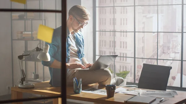 Professionele creatieve ontwerper zit op zijn bureau houdt laptop op de knieën en werken aan het project Early Morning. Creative Designe en Gaming Content Development Studio — Stockfoto