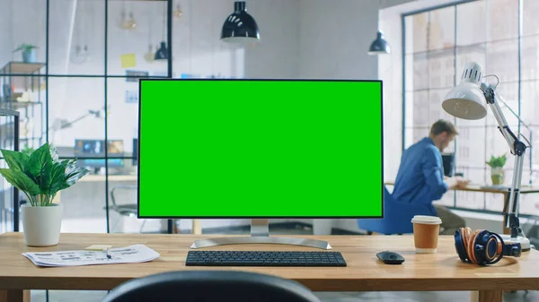 Wide Green Mock-up Screen Desktop Computer Μόνιμη στο γραφείο στο σύγχρονο δημιουργικό γραφείο. Στο παρασκήνιο Υψηλή οροφή Creative Loft για προγραμματιστές και σχεδιαστές, όπου ο επαγγελματίας που εργάζονται στο γραφείο του. — Φωτογραφία Αρχείου