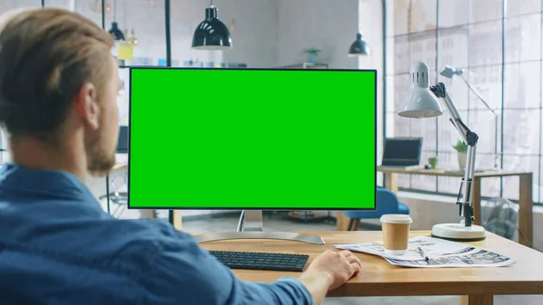 Omuz Fotoğrafı: Adam Masasında Otururken Masaüstü Bilgisayarını Yeşil Model Ekranı ile Kullanıyor. Arka planda Modern Açık Alan Yaratıcı İş Ofisi — Stok fotoğraf