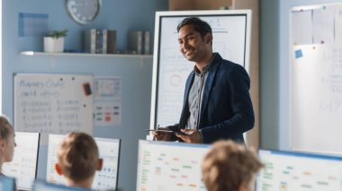 İlköğretim Okulu Bilgisayar Bilimi Sınıfı: Öğretmen Dijital Tablet Kullanıyor, Çeşitli Akıllı Çocuklar Grubuna Ders Açıklıyor. Modern eğitim alan çocuklar, Bilgisayar Bilimi öğrenin, Yazılım Programlama
