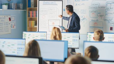 İlköğretim Sınıfı: Öğretmen Etkileşimli Dijital Beyaztahta Kullanıyor, Çeşitli Zeki Çocuklar Grubuna Ders Açıklıyor. Modern eğitim alan çocuklar, Bilgisayar Bilimi öğrenin, Yazılım Programlama