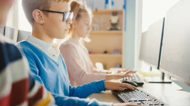 İlköğretim Okulu Sınıfı: Gözlüklü Akıllı Bir Çocuğun Portresi Kişisel Bilgisayarı Kullanıyor, İnterneti Güvenli Kullanmayı Öğreniyor, Yazılım Kodlaması İçin Programlama Dili. Çocuklar için Modern Eğitim