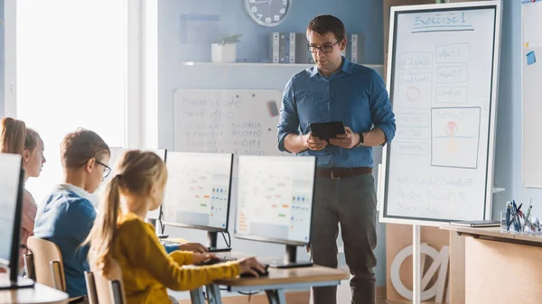 Basisschoolklas: Leraar maakt gebruik van interactieve digitale whiteboard, verklaart les aan diverse groep slimme kinderen. Kinderen krijgen modern onderwijs, computerwetenschappen leren, programmeren van software — Stockfoto