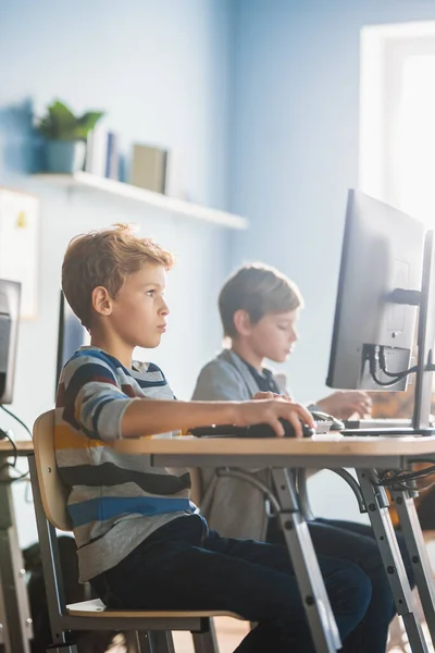 Aula de informática de la escuela primaria: Smart Little Schoolboy trabaja en computadoras personales, aprendiendo lenguaje de programación para codificación de software. Los escolares reciben educación moderna. —  Fotos de Stock