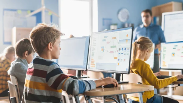 Elementary School Computer Science Classroom: Smart Little Schoolboy Lavora su personal computer, Impara il linguaggio di programmazione per la codifica del software. Studenti ottenere l'educazione moderna — Foto Stock