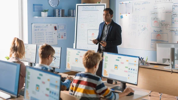 Clase de Ciencias de la Computación de la Escuela Primaria: El maestro utiliza la tableta digital, explica la lección a diversos grupos de niños inteligentes. Niños que reciben educación moderna, aprenden seguridad en Internet, programación de software —  Fotos de Stock