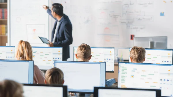 Clase de escuela primaria: El maestro utiliza pizarra digital interactiva, explica la lección a diversos grupos de niños inteligentes. Niños que reciben educación moderna, aprenden ciencias de la computación, programación de software —  Fotos de Stock