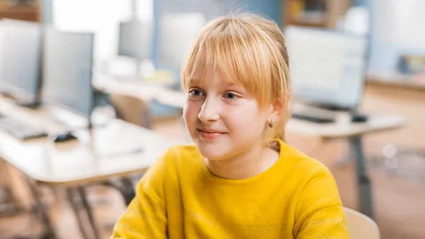 Portret van een schattig klein meisje met blond haar zittend aan haar schoolbureau, glimlacht gelukkig. Slimme kleine meid met een charmante glimlach zittend in de klaslokaal. Close-up Portretfoto — Stockfoto