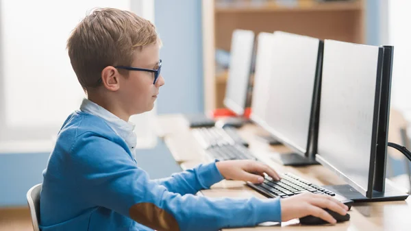Escuela Primaria de Ciencias de la Computación Aula: Lindo niño pequeño con gafas utiliza ordenador personal, aprendizaje de lenguaje de programación para la codificación de software. — Foto de Stock