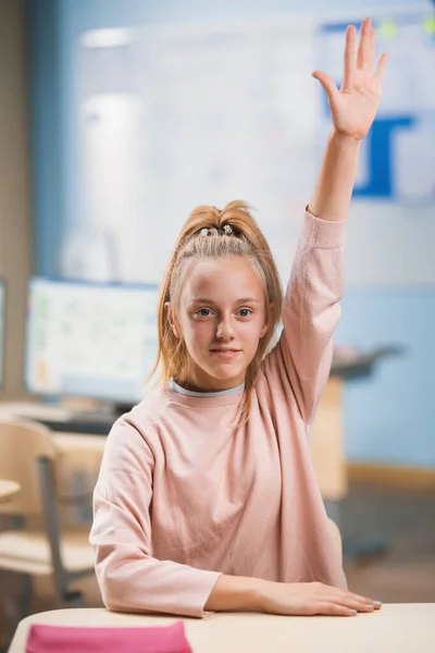 Szkoła podstawowa Klasa: Portret uroczej dziewczynki z blond włosami i kucykiem podnoszącej rękę z odpowiedzią. Genialny młody student zadaje pytanie. — Zdjęcie stockowe