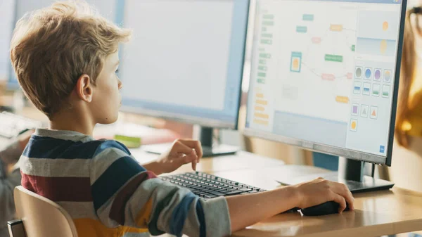 小学计算机科学课：聪明的小男生在个人电脑上工作，学习编程语言用于软件编码。接受现代教育的学童 — 图库照片