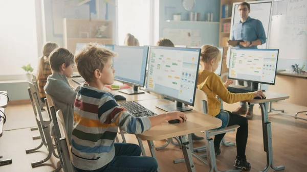 Basisschool Science Classroom: Docent onderwijst Smart Little Schoolkinderen die werken aan Personal Computers leren programmeren Taal voor Software Codering. Schoolkinderen krijgen modern onderwijs — Stockfoto