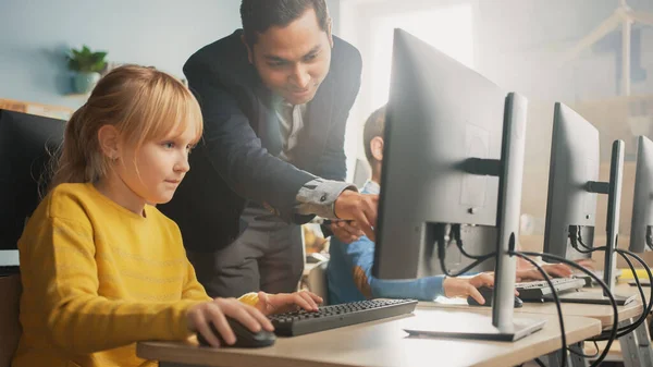 Sala de aula de ciências da escola primária: professor explica a uma pequena estudante inteligente como usar o computador pessoal, para aprender a linguagem de programação necessária para codificação de software. Educação moderna em progresso — Fotografia de Stock