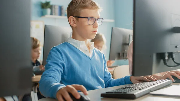Scuola elementare Aula: Ritratto di un ragazzo intelligente con occhiali utilizza Personal Computer, Imparare a utilizzare Internet in modo sicuro, Linguaggio di programmazione per la codifica del software. Educazione moderna per bambini — Foto Stock