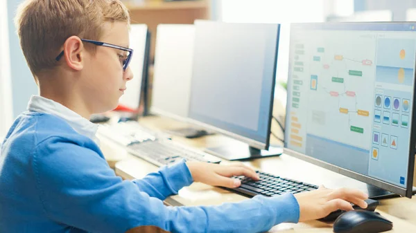 Scuola elementare aula di informatica: Ragazzino carino che indossa occhiali utilizza Personal Computer, Imparare il linguaggio di programmazione per la codifica del software, Sopra la spalla — Foto Stock