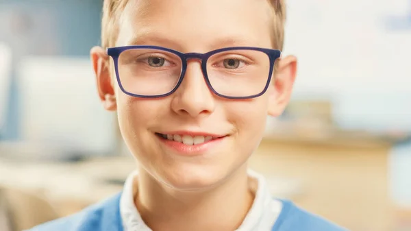 Porträtt av en söt liten pojke i glasögon skolbänk, ler lyckligt. Smart liten flicka med charmigt leende som sitter i klassrummet. Närbild Skott — Stockfoto