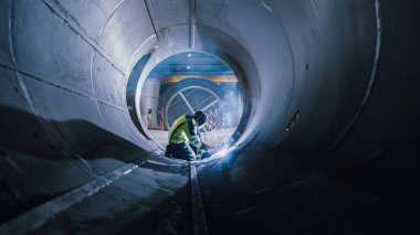 Profesyonel Ağır Sanayi Kaynak İşçisi Boru İçinde Çalışıyor, Kask Giyiyor ve Kaynak Yapmaya Başlıyor. Petrol, Doğal Gaz ve Yakıt Nakil Boru Hattı İnşaatı. Sanayi İmalat Fabrikası