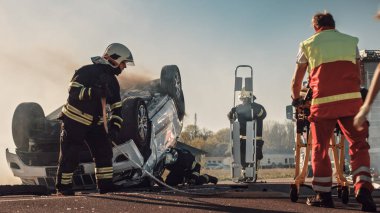 Trafik Kazası Olay Yeri İnceleme: Sağlık görevlileri ve İtfaiyeciler Yaralı Kurbanlar Aracın içinde Sıkıştı. Sıhhiyeciler sedye kullanır, ilk yardım uygular. İtfaiyeciler, İtfaiye 'den ekipmanları alın.