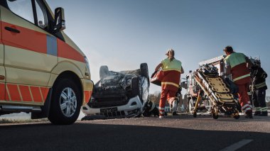 Trafik Kazası Olay Yeri İnceleme Ekibi: Ambulans ve İtfaiyeciler Kurtarma Ekibi, Rollover Aracında Tuzağa Düşenleri Kurtardı. Profesyoneller kurbanları temizler, ilk yardımı yapar, yangını söndürür.