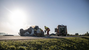 Trafik Kazası Olay Yeri İnceleme Ekibi: Ambulans ve İtfaiyeciler Kurtarma Ekibi, Rollover Aracında Tuzağa Düşenleri Kurtardı. Profesyoneller Kurbanları Kurtarır, İlk Yardım Verir.