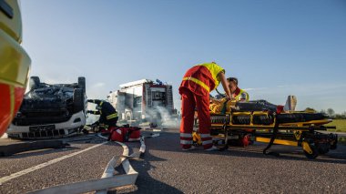 Trafik kazası sahnesinde, sedyelerin üzerinde yatan küçük bir kızın hayatını kurtaran sağlık görevlileri, ilk yardım aldı. İtfaiyeci Ana 'yı Kızına Götürdü. Arkaplanda Takla Aracı