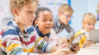 İlköğretim Okulu Bilgisayar Bilimi Sınıfı: Çocuklar Artırılmış Gerçeklik Yazılımı ile Dijital Tablet Bilgisayarlar ve Akıllı Telefonlar Kullanıyor, Heyecanlanıyorlar, Harikalar Dolu. STEM 'deki Çocuklar, Oynuyor ve Öğreniyor