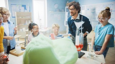 İlköğretim Okulu Kimya Sınıfı: Coşkulu Öğretmen, Beher 'de kimyasalları karıştırıp köpük fil diş macunu kullandıkları için çeşitli çocuk gruplarına bilim reaksiyon deneyleri öğretiyor 