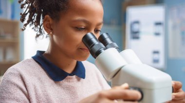 Mikroskop Altında Bakan Zeki Liseli Kız 'ın Portresi. İlkokulda şirin kız mikroskop kullanıyor. STEM Bilim, Teknoloji, Mühendislik ve Matematik Eğitim Programı