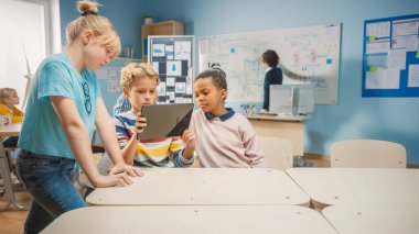 İlköğretim Okulu Bilgisayar Bilimi Sınıfı: İki Kız ve Erkek Artırılmış Gerçeklik Yazılımı ile Dijital Tablet Bilgisayar Kullanıyor, Heyecanlı, Merakla Dolu, Merak Dolu. STEM 'deki Çocuklar, Oynamak, Öğrenmek