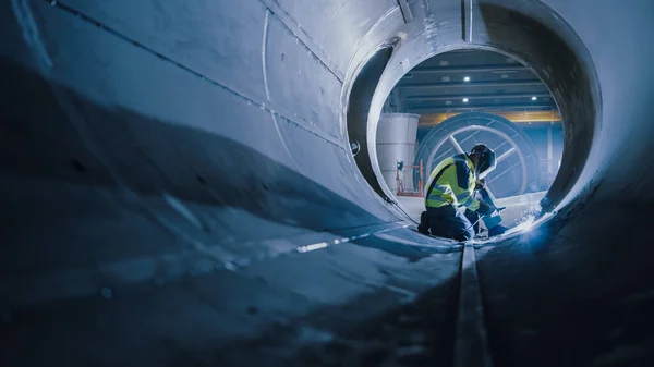 Professionell tung industri svetsare arbetar inuti röret, bär hjälm och börjar svetsning. Anläggning av rörledningen för transport av olja, naturgas och bränslen. Fabriken för industriell tillverkning. — Stockfoto