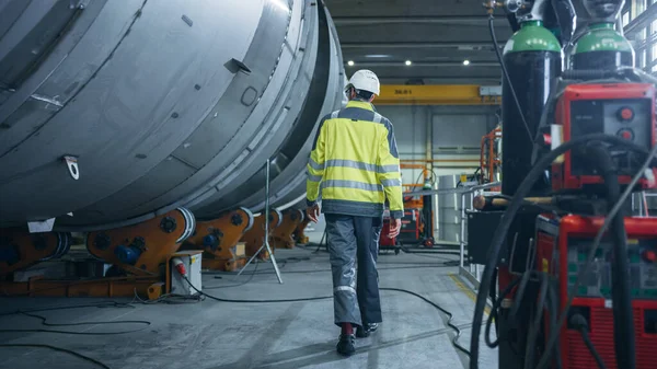 Siguiendo Shot of Heavy Industry Engineer Walking through Pipe Manufacturing Factory. Moderna instalación para el diseño y construcción de tuberías de transporte de petróleo, gas y combustibles de gran diámetro. — Foto de Stock