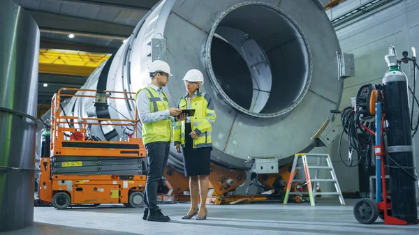 Dois engenheiros da indústria pesada estão na fábrica de fabricação de tubos, use o computador de tablet digital, discuta. Instalação para Construção de Produtos de Transporte de Petróleo, Gás e Combustível — Fotografia de Stock