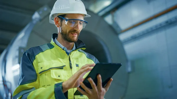 Porträtt av professionell tung industri ingenjör arbetare bär säkerhet enhetlig och hårt hatt använder Tablet Computer. I bakgrunden Byggande Fabriken för olja, gas och bränslen Transport Pipeline — Stockfoto