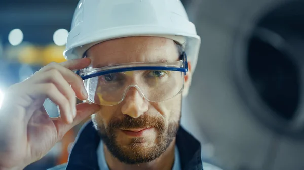 专业重工业工程师穿着安全制服、护目镜和硬帽衫的画像。背景下的无重点大型工业厂房 — 图库照片