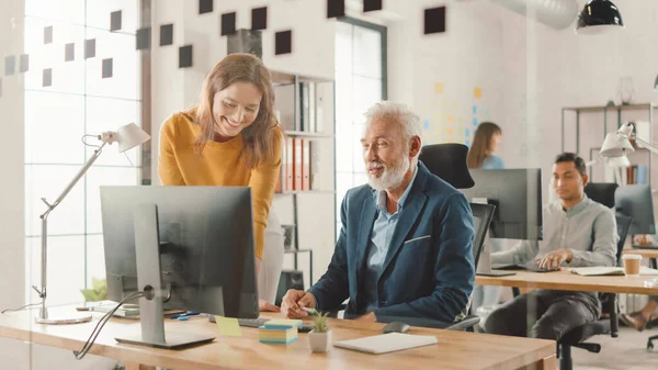 Handsome Middle Aged Creative Engineer Sitting at the Desk working on Desktop Computer Has Discussion with Beautiful Female Project Manager. Office with Friendly Colleagues Chatting, Finding Solutions — Stock Photo, Image