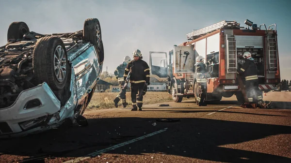 Rescue Team of Firefighters Arrive on the Car Crash Traffic Accident Scene on their Fire Engine. Firemen Grab their Tools, Equipment and, Gear from Fire Truck, Rush to Help Injured, Trapped People