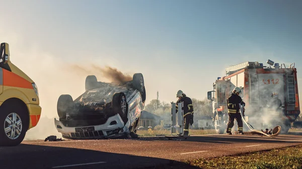 Am Unfallort: Sanitäter und Feuerwehrleute retten Verletzte, die im Fahrzeug eingeklemmt sind. Sanitäter benutzen Tragen, leisten Erste Hilfe. Feuerwehr greift nach Ausrüstung. — Stockfoto
