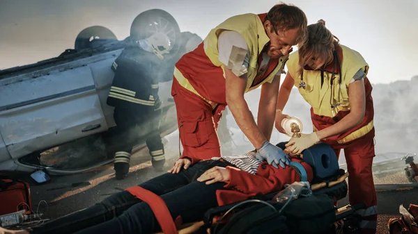 På bilkraschen Trafikolycka Scen: Paramedics Rädda livet på en kvinnlig offer som ligger på bårar. De applicerar Oxygen Mask, Do Cardiopulmonary återupplivning HLR och utföra första hjälpen — Stockfoto