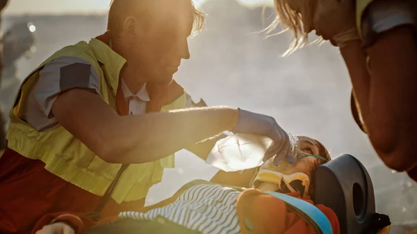 På bilkraschen Trafikolycka Scen: Paramedics Rädda livet på en kvinnlig offer som ligger på bårar. De lyssnar på hjärtslag, applicerar syrgasmask och ger första hjälpen.. — Stockfoto